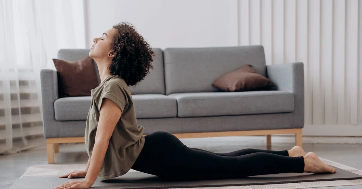 Une jeune femme sereine pratiquant le yoga à la maison, adoptant le bien-être et la relaxation.