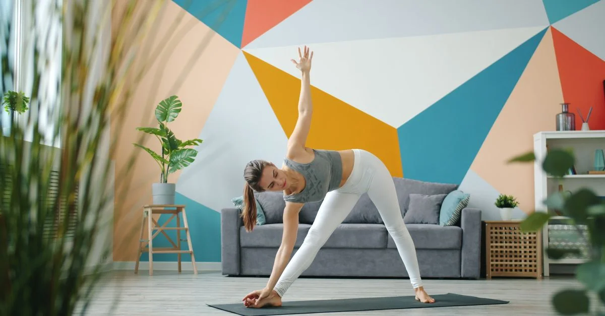 Femme faisant du yoga à la maison avec un design mural géométrique coloré, améliorant la concentration.