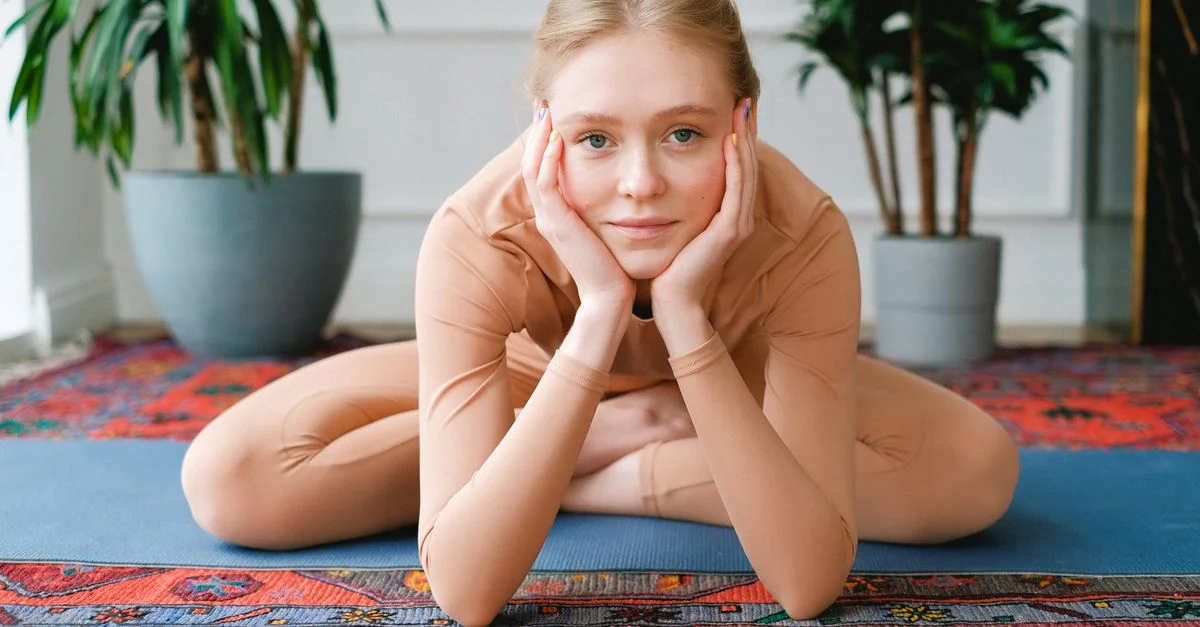 Femme pratiquant le yoga à l'intérieur sur un tapis, favorisant la relaxation et la pleine conscience.