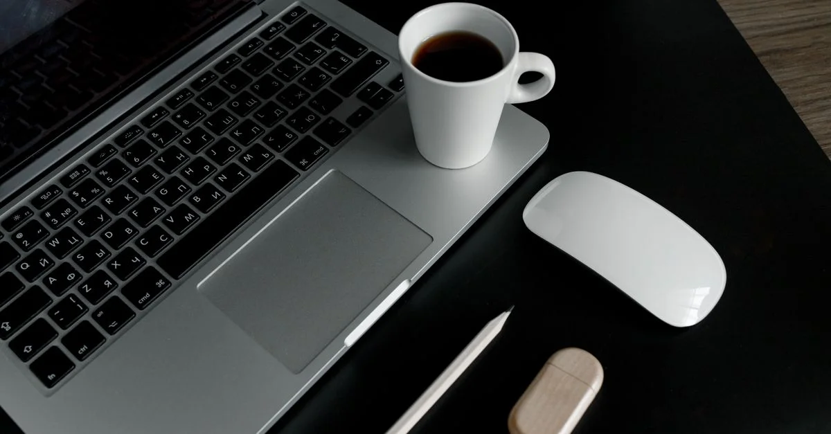 Un bureau élégant et minimaliste avec un ordinateur portable, une tasse de café et des accessoires.
